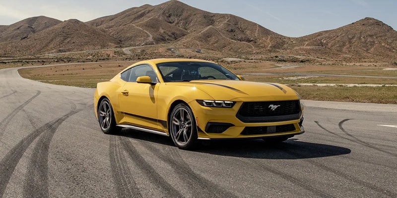 Yellow Mustang Vehicle Moving On A Road Passing Through Hills